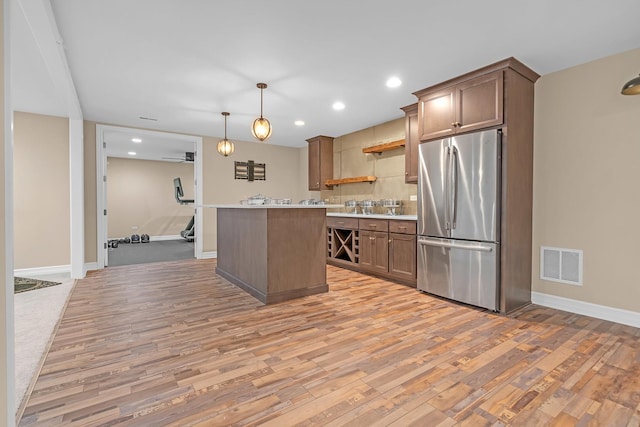 kitchen featuring open shelves, light countertops, visible vents, light wood-style flooring, and freestanding refrigerator