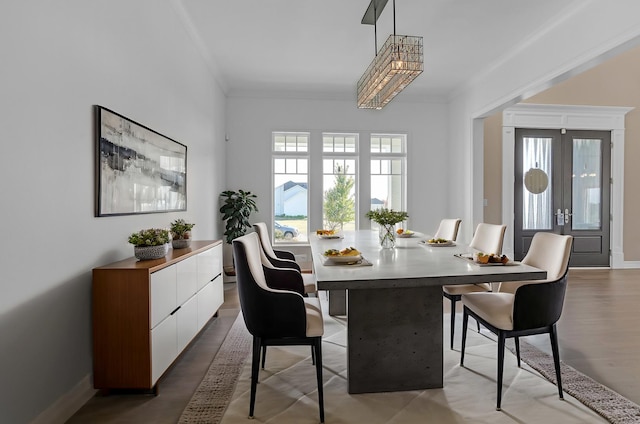 dining room with baseboards, ornamental molding, a wealth of natural light, and wood finished floors