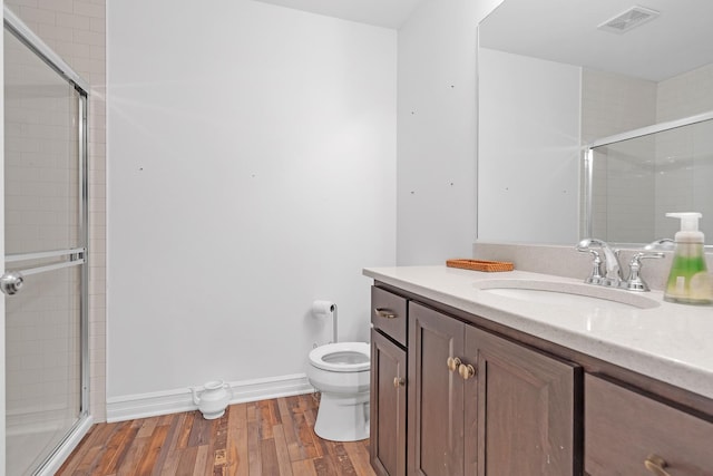 full bath featuring toilet, wood finished floors, vanity, visible vents, and a shower stall