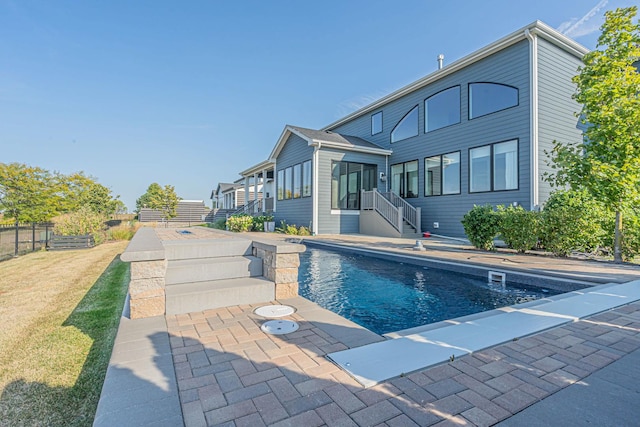 back of property featuring a fenced in pool, a sunroom, a patio area, fence, and stairs