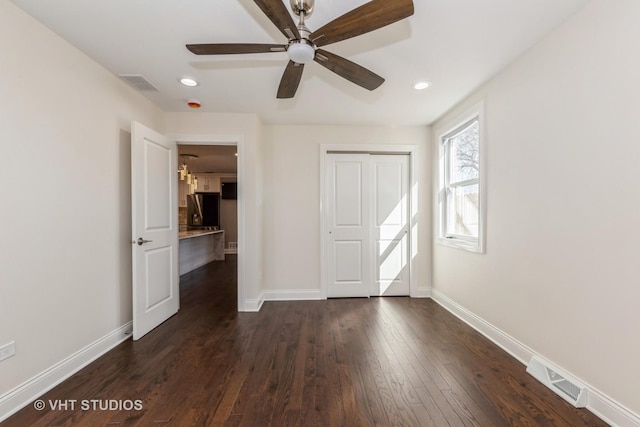 unfurnished bedroom with visible vents, baseboards, dark wood-type flooring, and refrigerator with ice dispenser