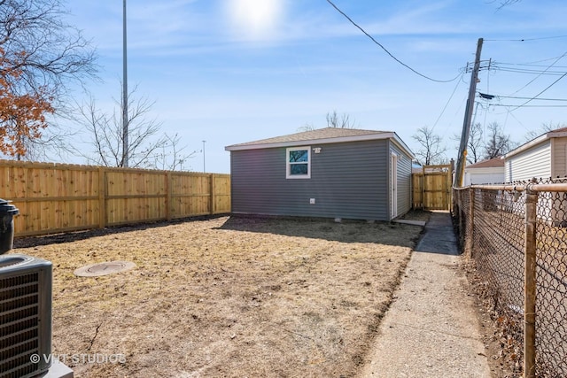 rear view of house with cooling unit, an outbuilding, and a fenced backyard