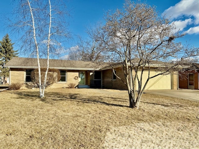 back of property with a yard, brick siding, driveway, and an attached garage