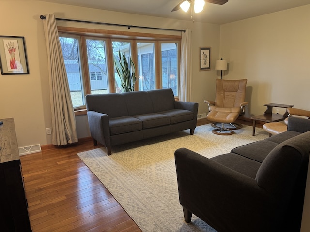 living room with visible vents, ceiling fan, and hardwood / wood-style flooring