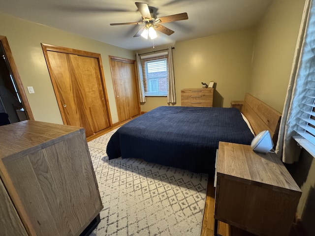 bedroom with ceiling fan and multiple closets