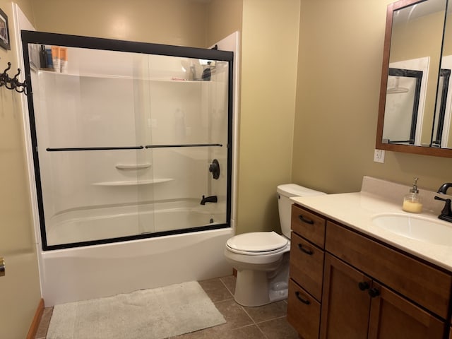 full bathroom featuring vanity, shower / bath combination with glass door, tile patterned flooring, and toilet