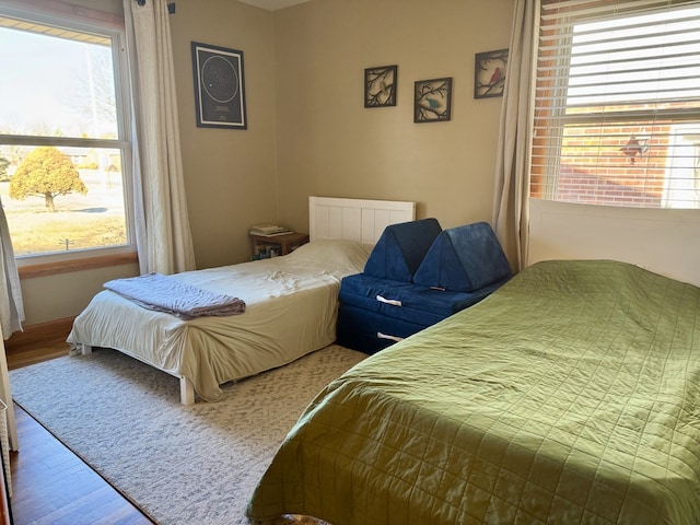 bedroom with multiple windows and wood finished floors