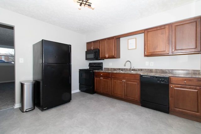 kitchen with black appliances, dark countertops, brown cabinetry, and a sink