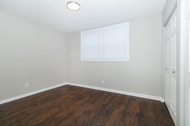 empty room with dark wood finished floors and baseboards