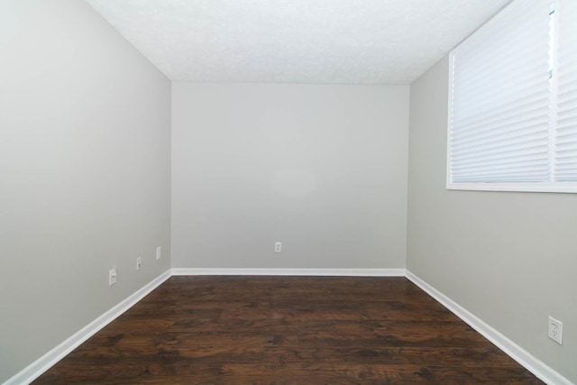 spare room with baseboards and dark wood finished floors