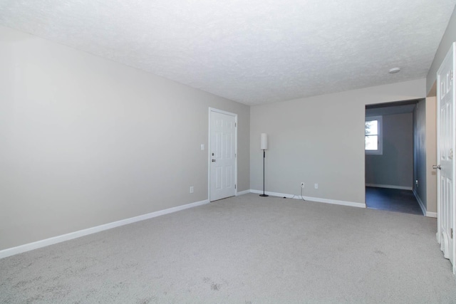 spare room with baseboards, light carpet, and a textured ceiling