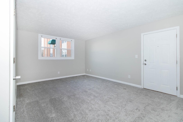 carpeted empty room featuring a textured ceiling and baseboards