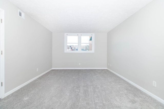 spare room with visible vents, a textured ceiling, carpet, and baseboards