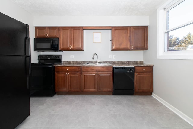 kitchen with dark countertops, brown cabinets, black appliances, and a sink