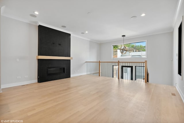 unfurnished living room with ornamental molding, a large fireplace, baseboards, and wood finished floors