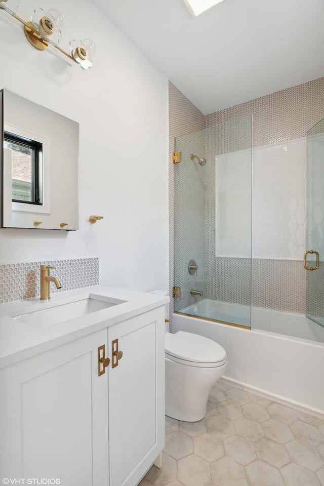 bathroom featuring shower / bath combination with glass door, tile patterned flooring, vanity, and toilet