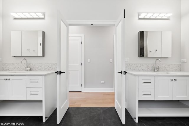 full bathroom with tile patterned flooring, two vanities, a sink, and decorative backsplash