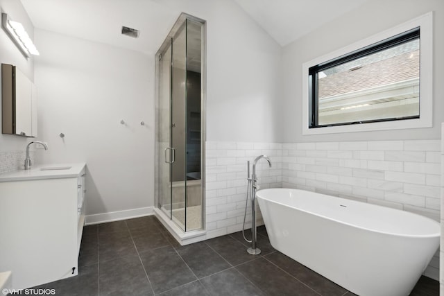 full bath with a soaking tub, vaulted ceiling, vanity, a shower stall, and tile patterned floors