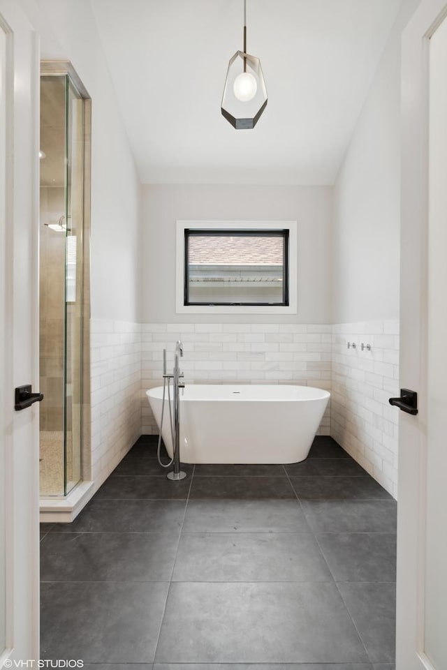 bathroom featuring a stall shower, a wainscoted wall, tile patterned floors, a freestanding bath, and tile walls