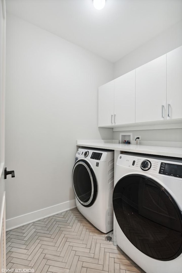 clothes washing area featuring separate washer and dryer, cabinet space, and baseboards