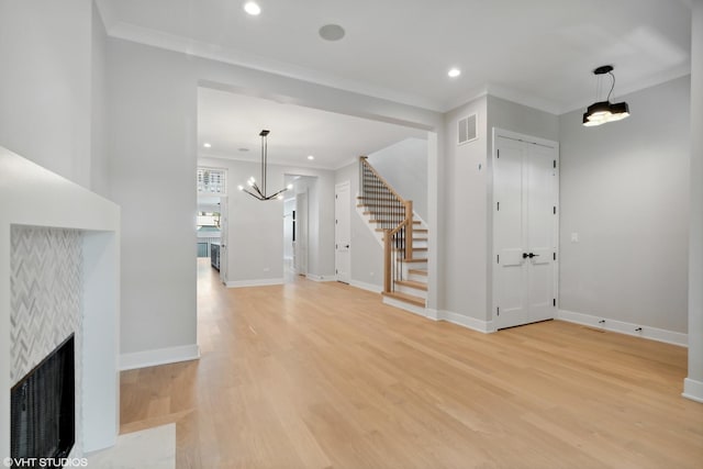 unfurnished living room featuring a fireplace with flush hearth, visible vents, light wood-style floors, stairway, and crown molding