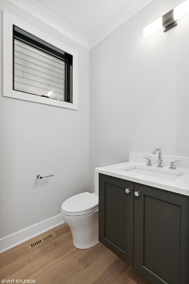 bathroom featuring toilet, wood finished floors, visible vents, vanity, and baseboards