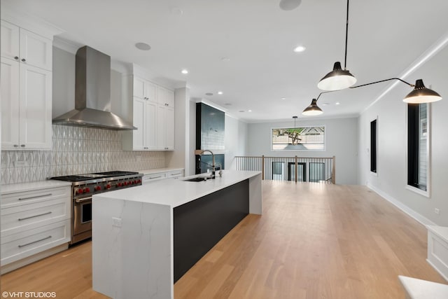 kitchen featuring tasteful backsplash, wall chimney exhaust hood, light countertops, double oven range, and a sink