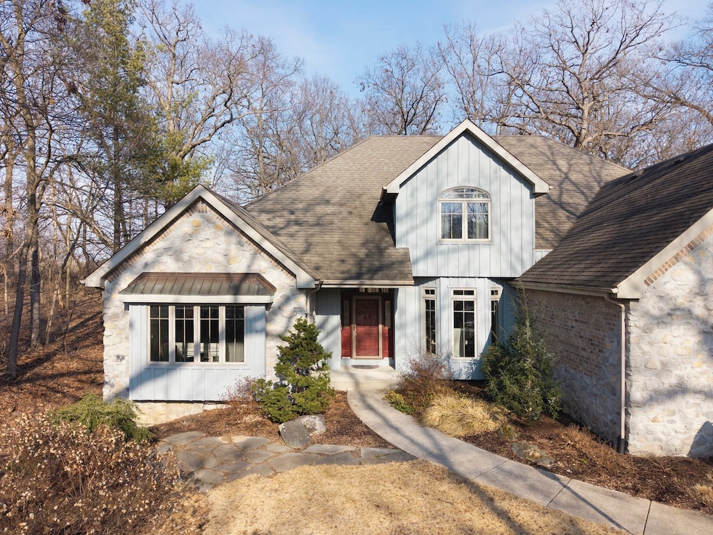 view of front of house with a shingled roof, stone siding, and board and batten siding