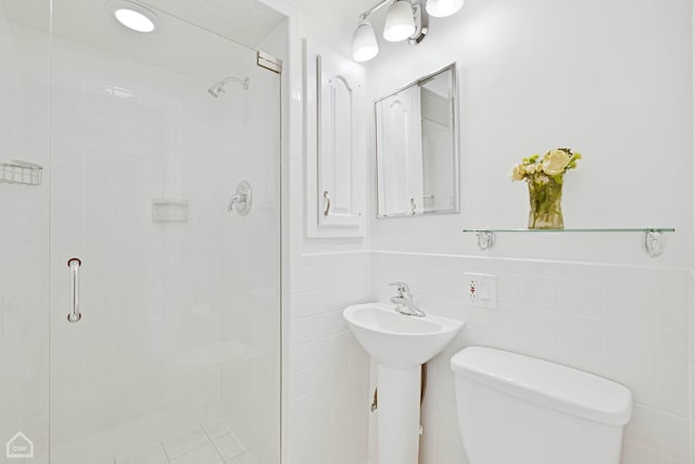 bathroom featuring toilet, a stall shower, and tile walls