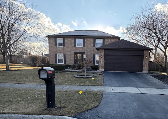 traditional home featuring driveway, solar panels, a front lawn, a garage, and brick siding