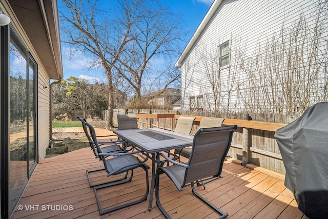 wooden deck featuring a fenced backyard, a grill, and outdoor dining space