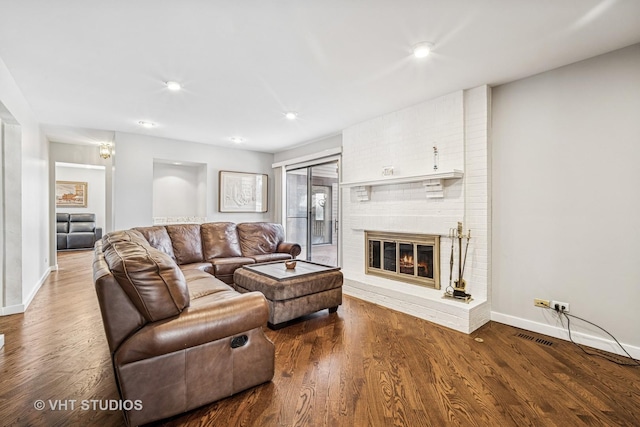 living area with visible vents, wood finished floors, recessed lighting, baseboards, and a brick fireplace