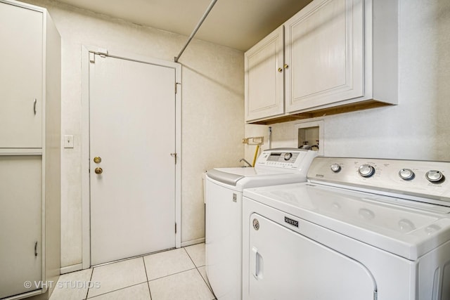 washroom with light tile patterned flooring, cabinet space, and washing machine and clothes dryer