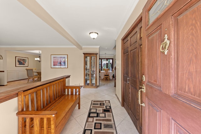 foyer entrance with light tile patterned floors, a chandelier, and crown molding