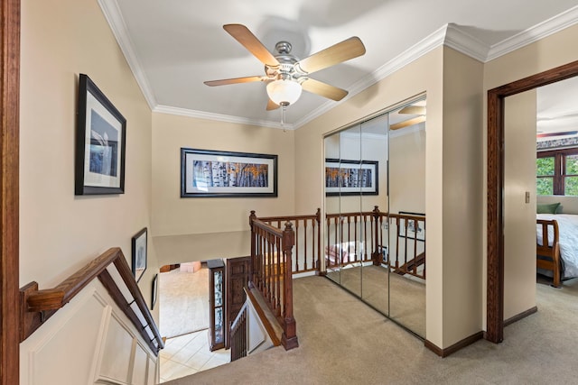 hallway featuring carpet floors, ornamental molding, and an upstairs landing