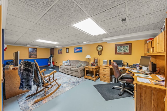 home office with concrete flooring, a drop ceiling, and visible vents