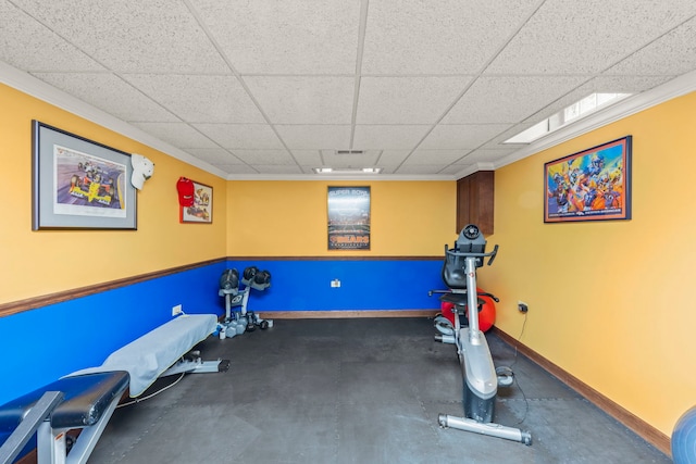 workout area with ornamental molding, a paneled ceiling, and baseboards