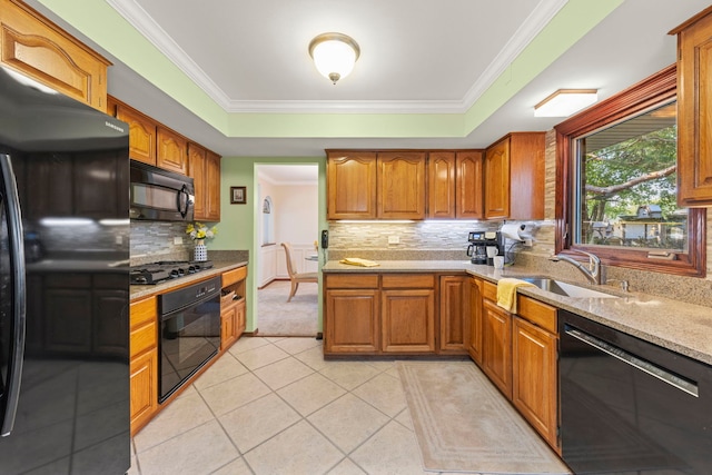 kitchen with crown molding, light tile patterned floors, a raised ceiling, a sink, and black appliances