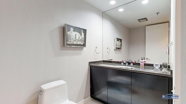 half bath featuring recessed lighting, vanity, and toilet