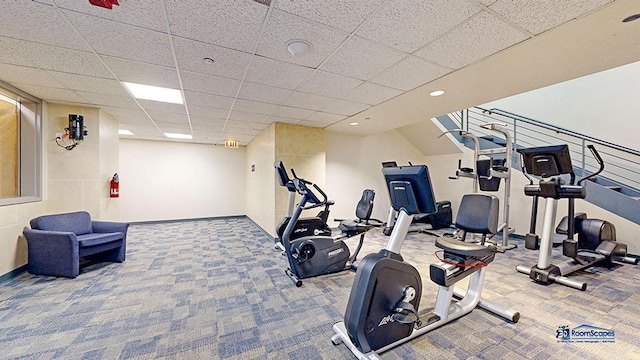 workout area featuring baseboards, a drop ceiling, and carpet flooring