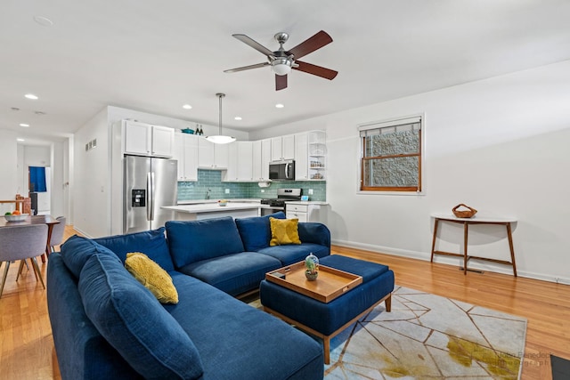 living room with recessed lighting, a ceiling fan, light wood-type flooring, and baseboards