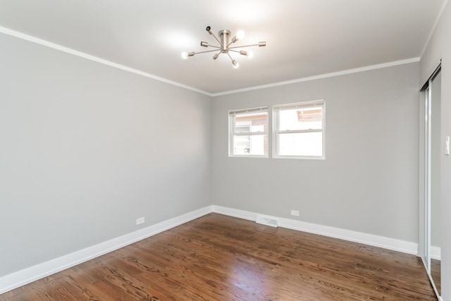 empty room with baseboards, visible vents, wood finished floors, and ornamental molding