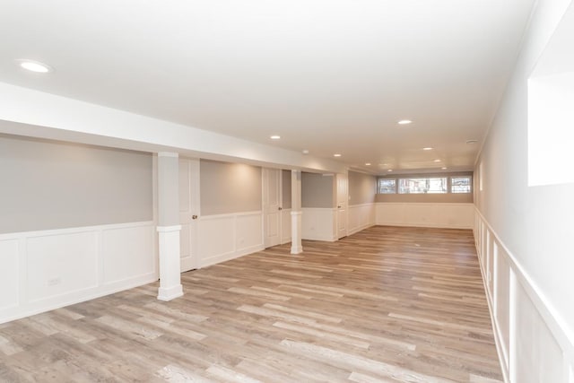 basement with a wainscoted wall, light wood finished floors, and recessed lighting