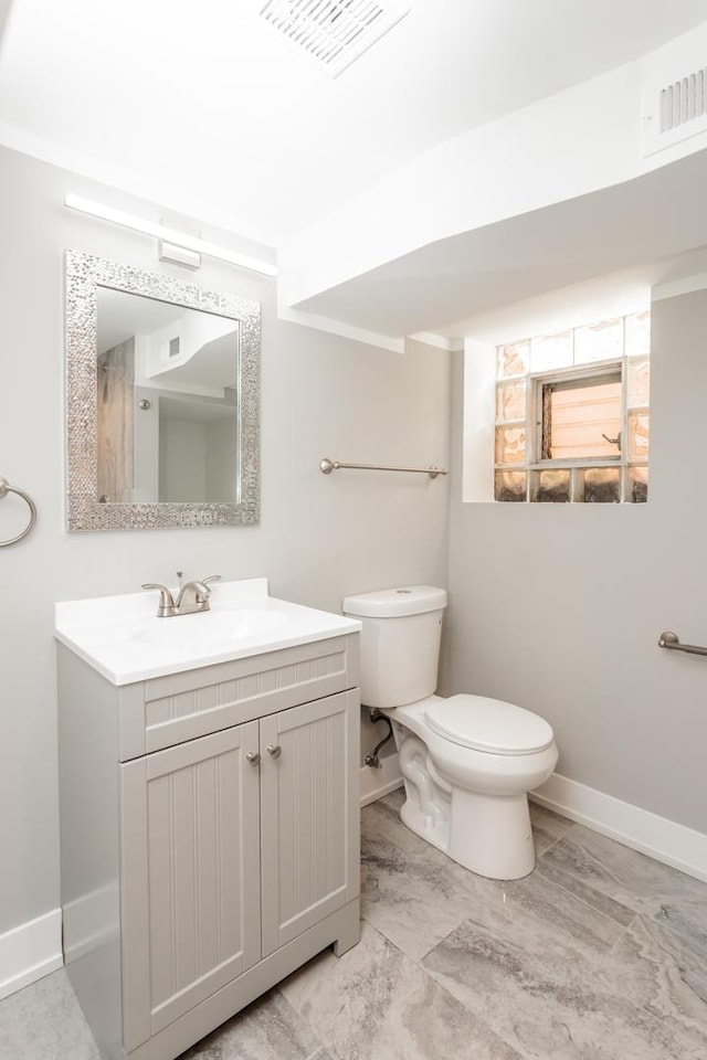 bathroom featuring visible vents, vanity, toilet, and baseboards