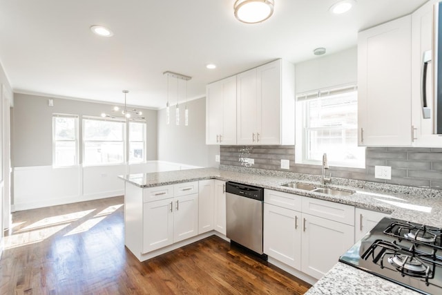 kitchen featuring a peninsula, stainless steel dishwasher, white cabinetry, a sink, and black gas stovetop