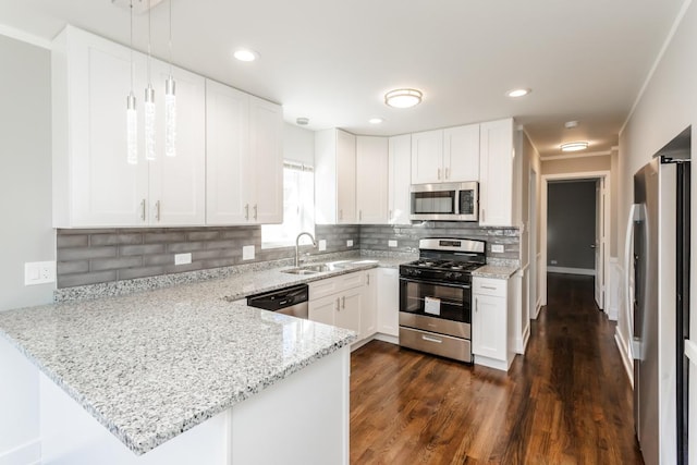 kitchen with tasteful backsplash, appliances with stainless steel finishes, a sink, light stone countertops, and a peninsula