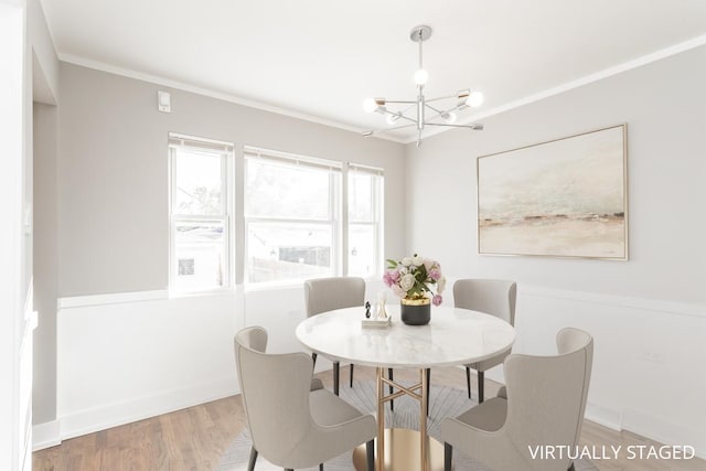 dining room featuring a chandelier, ornamental molding, light wood-style flooring, and baseboards