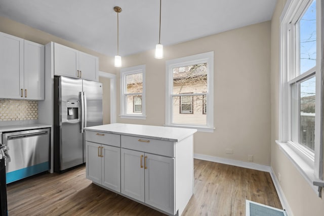 kitchen featuring decorative light fixtures, tasteful backsplash, visible vents, appliances with stainless steel finishes, and wood finished floors