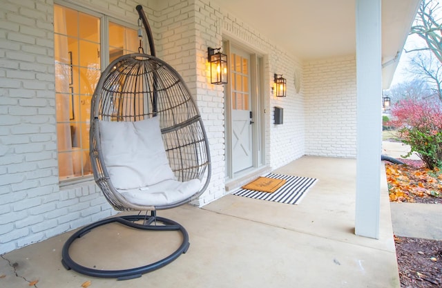 property entrance with a porch and brick siding