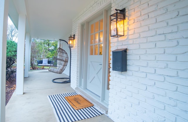 view of exterior entry featuring covered porch and brick siding